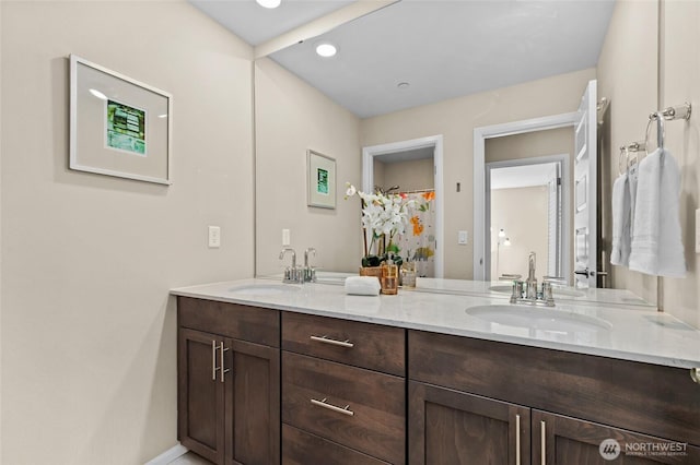 full bath featuring double vanity and baseboards