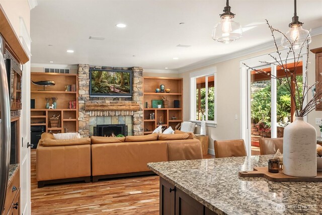 living room with crown molding, a fireplace, light wood finished floors, and recessed lighting