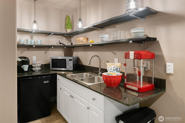 kitchen featuring stainless steel microwave, open shelves, a sink, and dark countertops