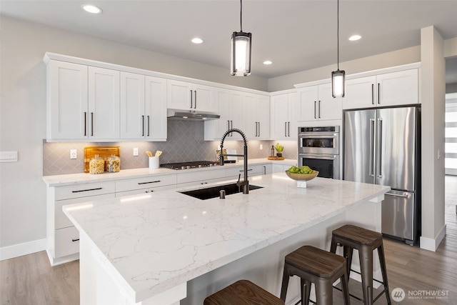 20022 7th Ave SE, Bothell, WA 98012 - kitchen with appliances with stainless steel finishes, a sink, under cabinet range hood, light wood-style flooring, and recessed lighting
