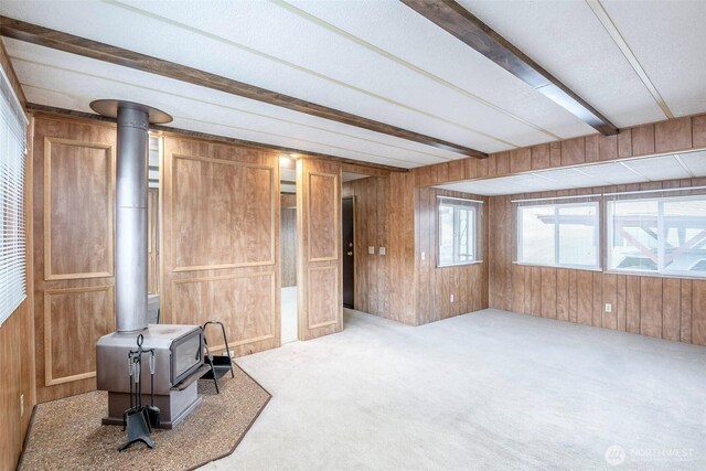 5705 113th Ave E Unit 68, Puyallup, WA 98372 - unfurnished living room featuring a wood stove, wooden walls, carpet flooring, and beam ceiling