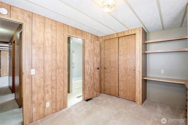 5705 113th Ave E Unit 68, Puyallup, WA 98372 - unfurnished bedroom featuring carpet, wooden walls, a closet, connected bathroom, and a textured ceiling