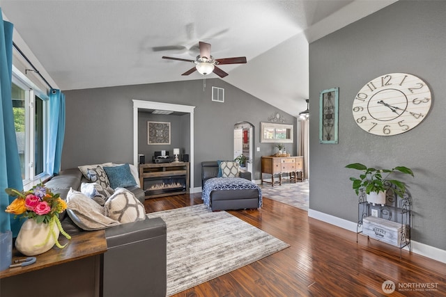 living area featuring a ceiling fan, lofted ceiling, arched walkways, wood finished floors, and baseboards