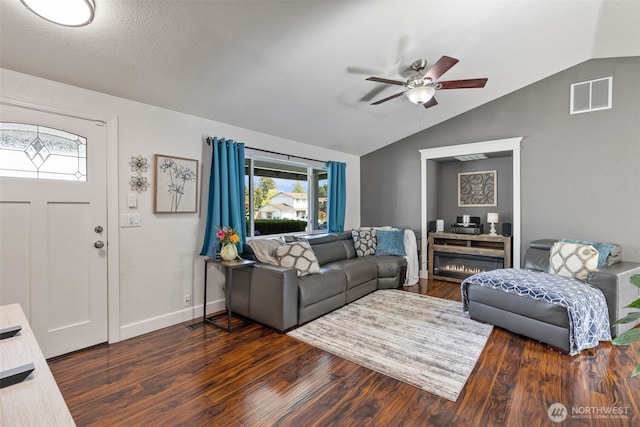 living area featuring lofted ceiling, ceiling fan, dark wood-type flooring, plenty of natural light, and baseboards