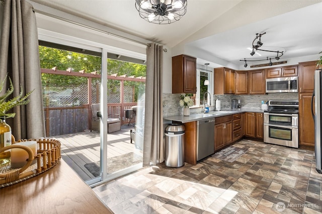 kitchen with stainless steel appliances, a sink, a chandelier, plenty of natural light, and vaulted ceiling