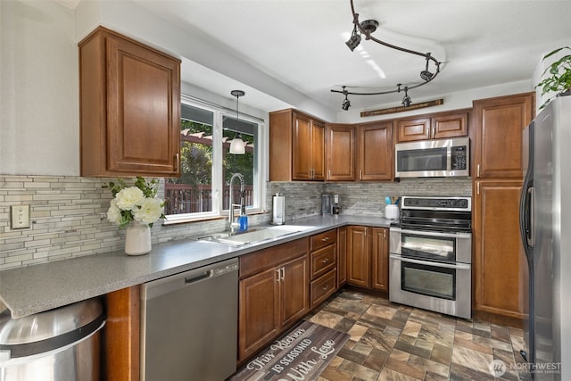 kitchen with appliances with stainless steel finishes, a sink, brown cabinets, and decorative backsplash