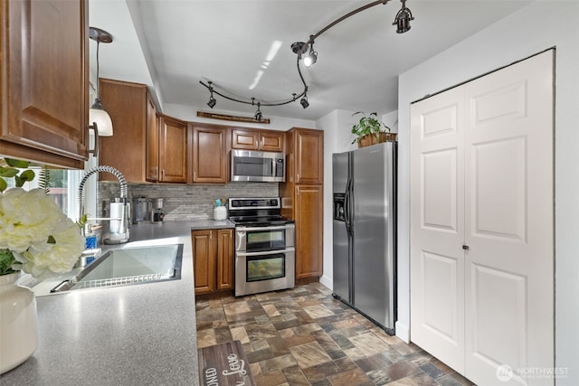 kitchen featuring appliances with stainless steel finishes, brown cabinetry, a sink, decorative backsplash, and light countertops