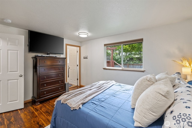 bedroom with dark wood-type flooring and baseboards
