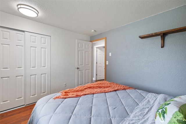 bedroom with wood finished floors, a textured ceiling, a closet, and a textured wall