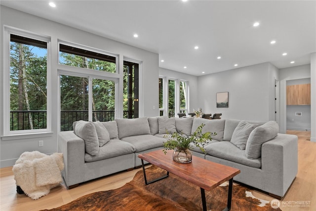 living area featuring plenty of natural light, light wood-style floors, recessed lighting, and baseboards