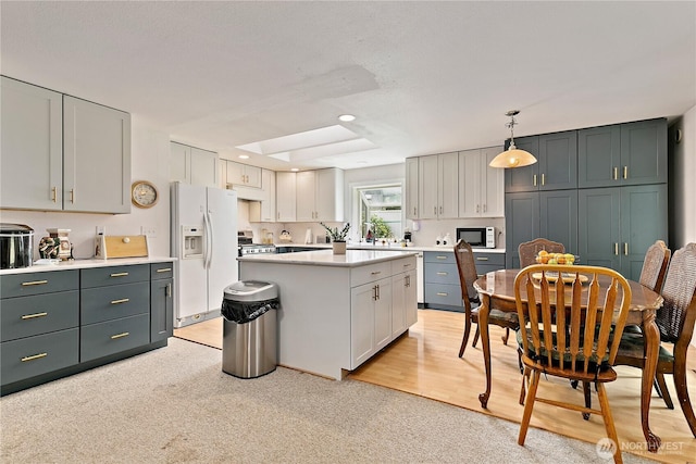 19414 112th Ave E, Graham, WA 98338 - kitchen featuring white appliances, light countertops, a kitchen island, light carpet, and pendant lighting