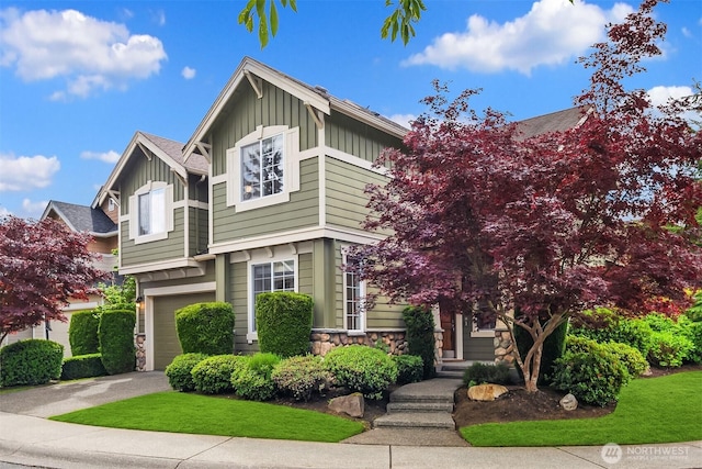 view of front of home featuring board and batten siding, a garage, stone siding, and driveway