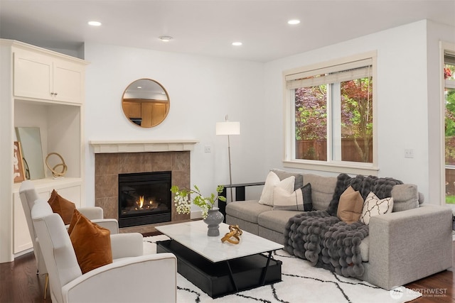living area with wood finished floors, recessed lighting, and a tiled fireplace