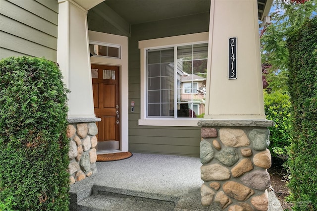 view of exterior entry featuring covered porch and stone siding
