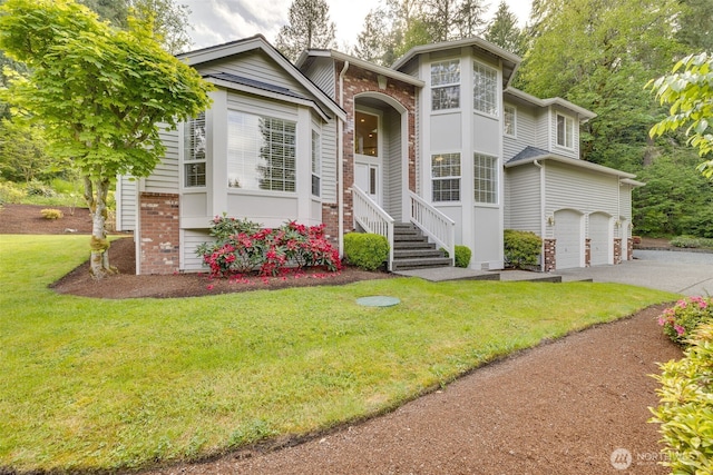 view of front of home with brick siding, a front yard, asphalt driveway, and an attached garage