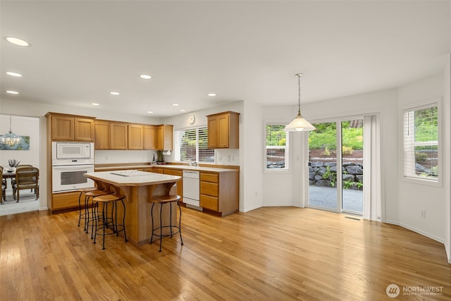 kitchen with white appliances, light countertops, plenty of natural light, a breakfast bar, and recessed lighting