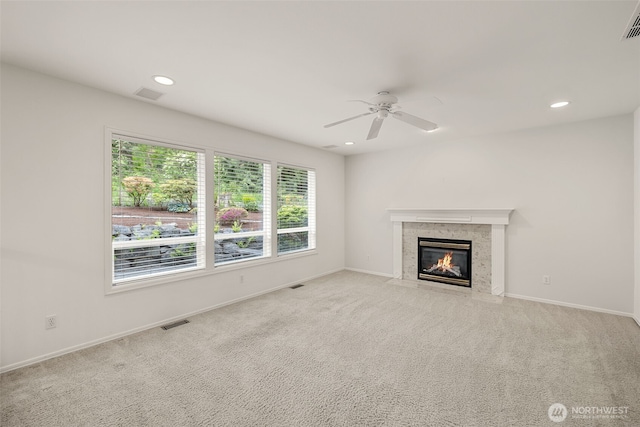 unfurnished living room featuring a premium fireplace, ceiling fan, recessed lighting, baseboards, and carpet flooring