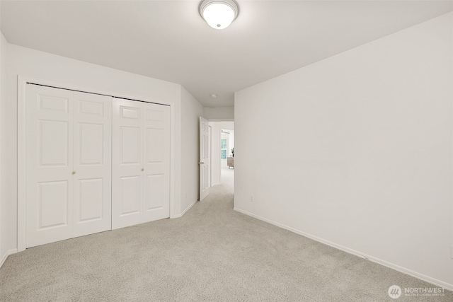 unfurnished bedroom featuring light colored carpet, baseboards, and a closet