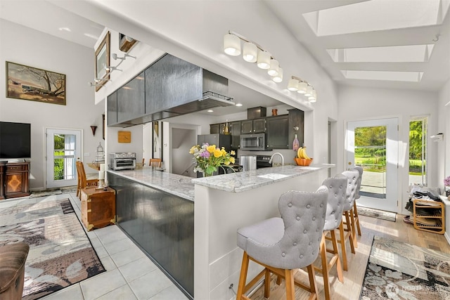 8894 Giles Rd, Blaine, WA 98230 - kitchen with stainless steel appliances, a peninsula, light stone countertops, a skylight, and a sink