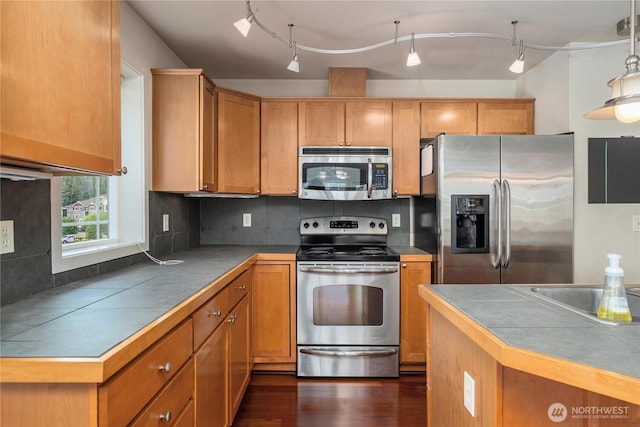 13426 97th Ave E Unit 303, Puyallup, WA 98373 - kitchen with appliances with stainless steel finishes, tile countertops, tasteful backsplash, and dark wood-style floors