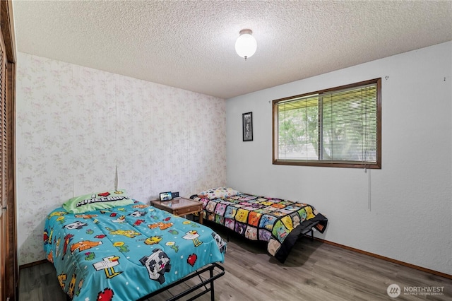 1826 156th St NE, Arlington, WA 98223 - bedroom featuring wood finished floors, wallpapered walls, a textured ceiling, and baseboards