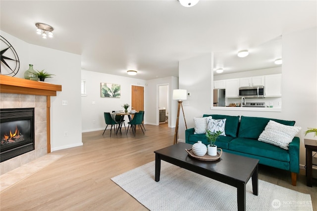 9402 187th St E, Puyallup, WA 98375 - living area featuring light wood-style flooring, a tiled fireplace, and baseboards