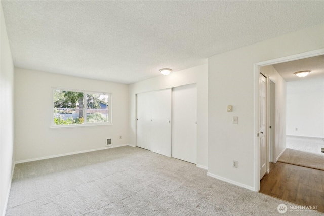 unfurnished bedroom with carpet flooring, a textured ceiling, baseboards, and a closet