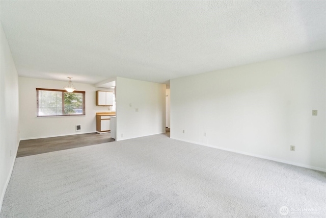 unfurnished living room featuring carpet flooring, a textured ceiling, and baseboards