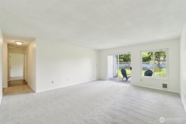 empty room featuring a textured ceiling, carpet floors, and baseboards