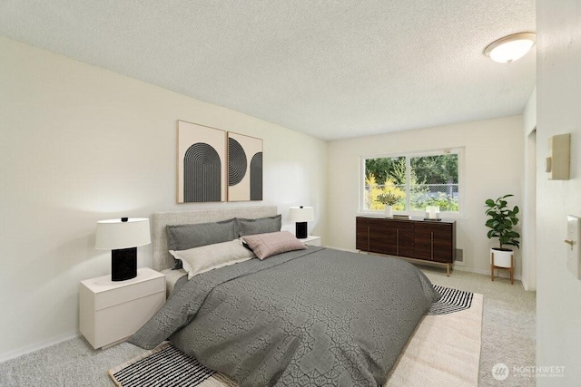 bedroom with light carpet, a textured ceiling, and baseboards