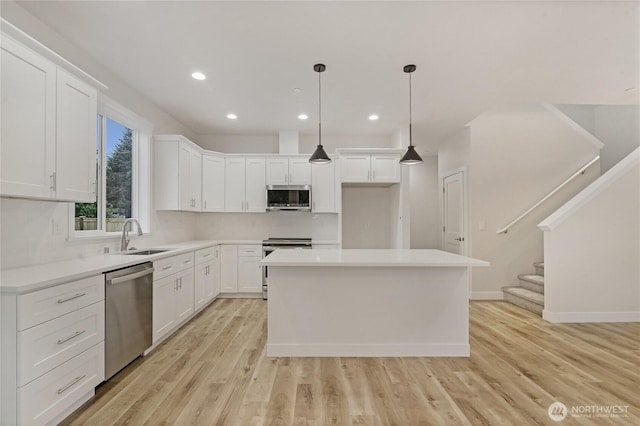 kitchen featuring appliances with stainless steel finishes, a sink, decorative backsplash, light wood-style floors, and recessed lighting