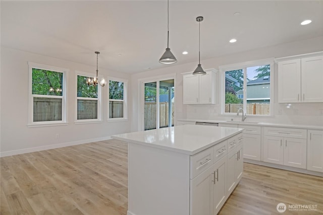 kitchen featuring a sink, healthy amount of natural light, a kitchen island, light countertops, and recessed lighting