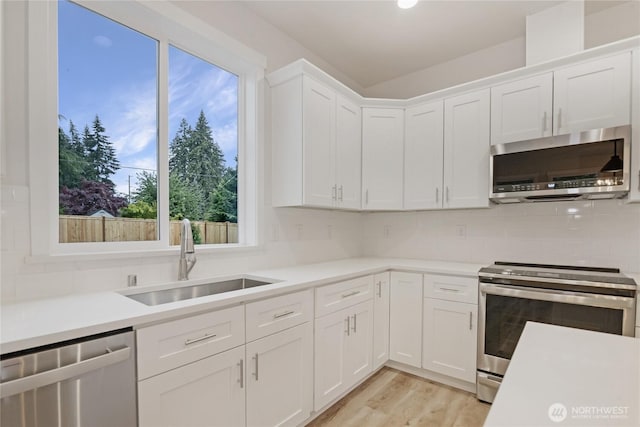 kitchen with stainless steel appliances, a sink, light countertops, and white cabinets
