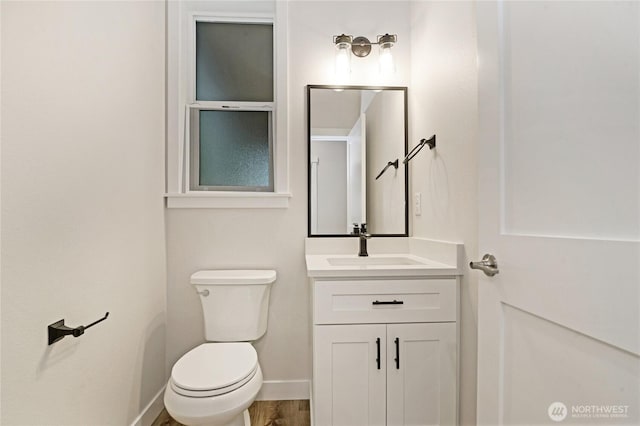 bathroom featuring toilet, vanity, and baseboards