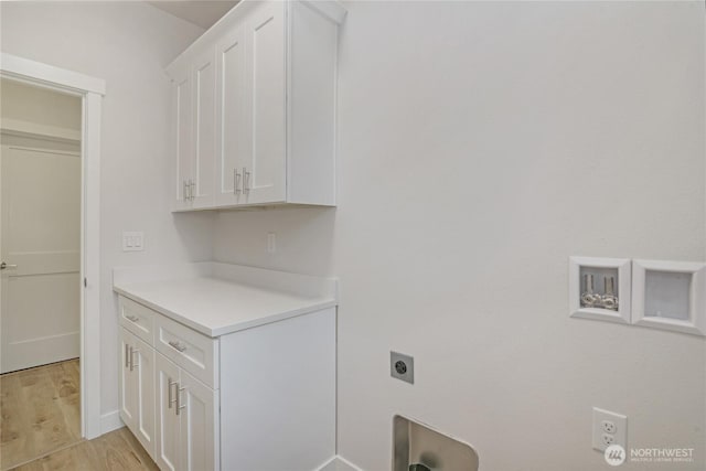 laundry area featuring hookup for an electric dryer, cabinet space, and light wood-style floors
