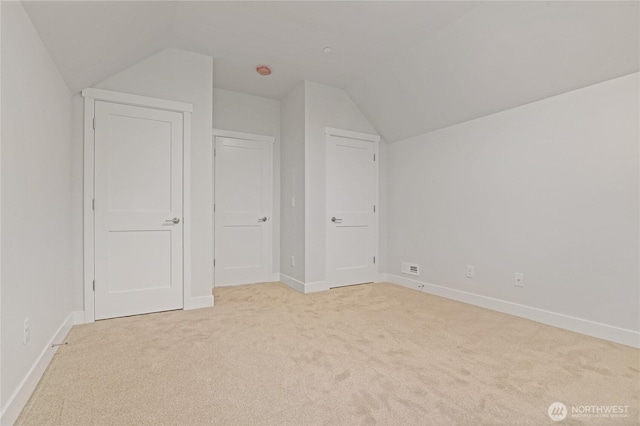 additional living space featuring lofted ceiling, light carpet, and baseboards