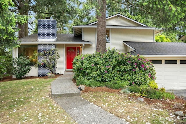 view of front of property featuring a garage, a chimney, a shingled roof, and a front yard