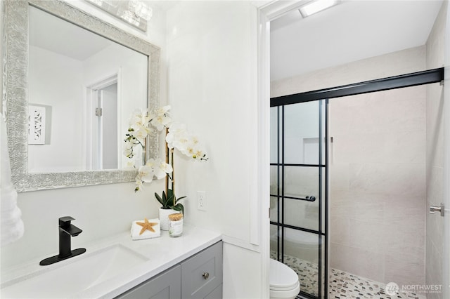 bathroom with tiled shower, toilet, and vanity
