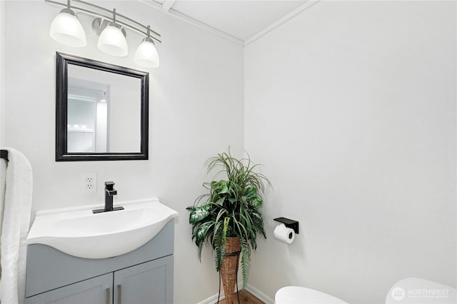 bathroom with toilet, vanity, crown molding, and baseboards