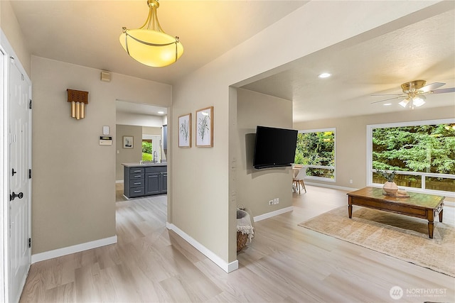 hallway featuring plenty of natural light, light wood-type flooring, baseboards, and recessed lighting