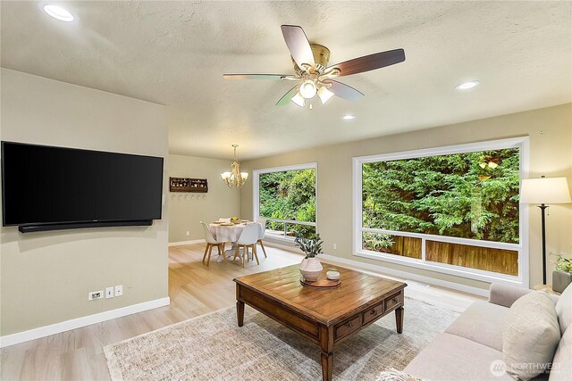 living area with a chandelier, light wood-style flooring, a textured ceiling, a ceiling fan, and recessed lighting