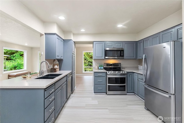 kitchen with appliances with stainless steel finishes, a sink, plenty of natural light, light countertops, and recessed lighting