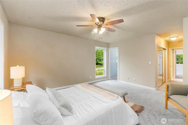 carpeted bedroom featuring a textured ceiling, baseboards, and ceiling fan