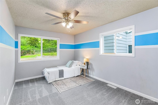 bedroom featuring carpet, baseboards, a textured ceiling, and a ceiling fan