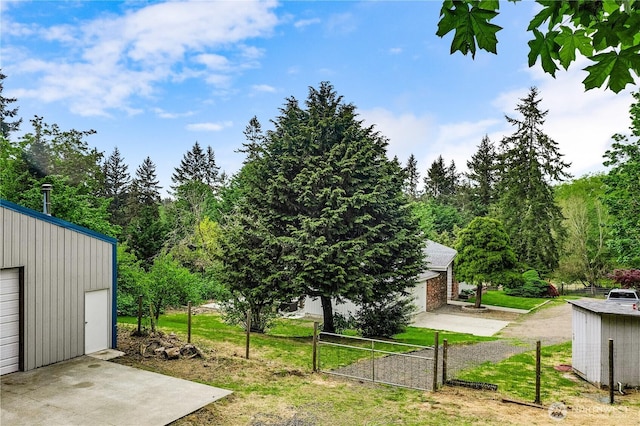view of yard featuring an outbuilding, fence, and driveway
