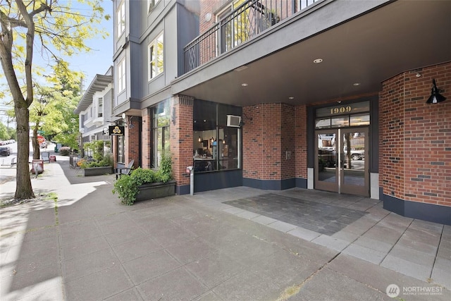 view of exterior entry with french doors, brick siding, and a wall mounted AC