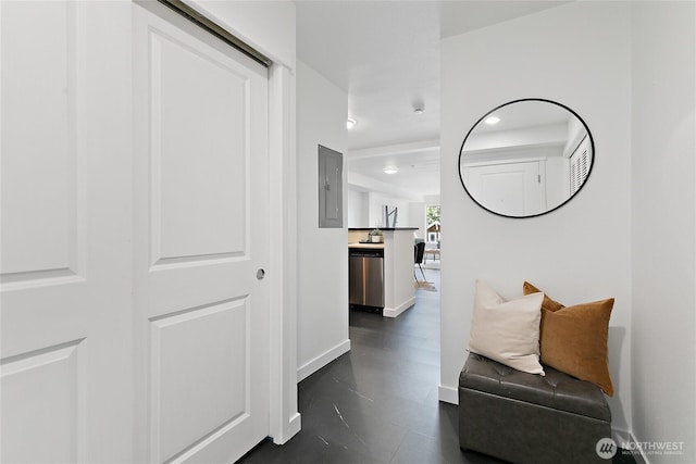 hallway featuring baseboards and electric panel