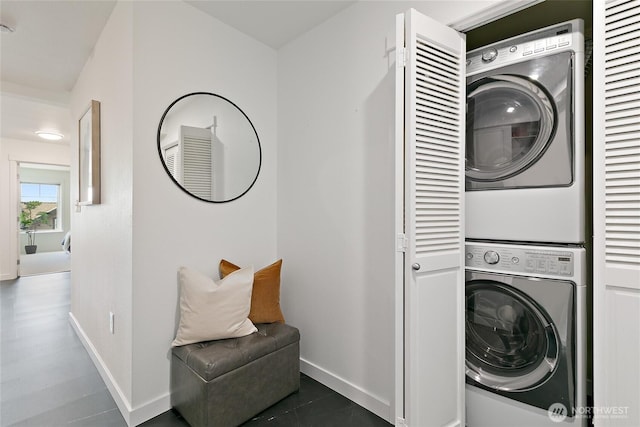 washroom with stacked washer and clothes dryer and baseboards