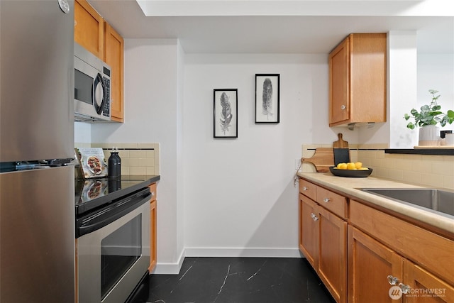kitchen featuring stainless steel appliances, decorative backsplash, baseboards, and dark tile patterned flooring