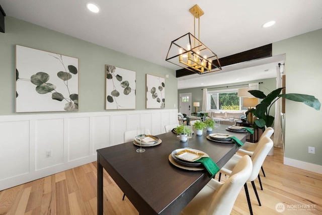 dining space with light wood-style floors, a chandelier, wainscoting, a decorative wall, and recessed lighting